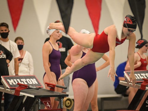 girls swim student diving into water girls swim student diving into water
